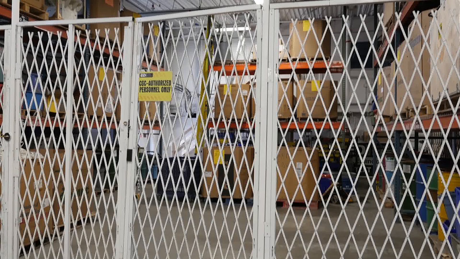 The locked gate of the controlled goods cage, with its sign