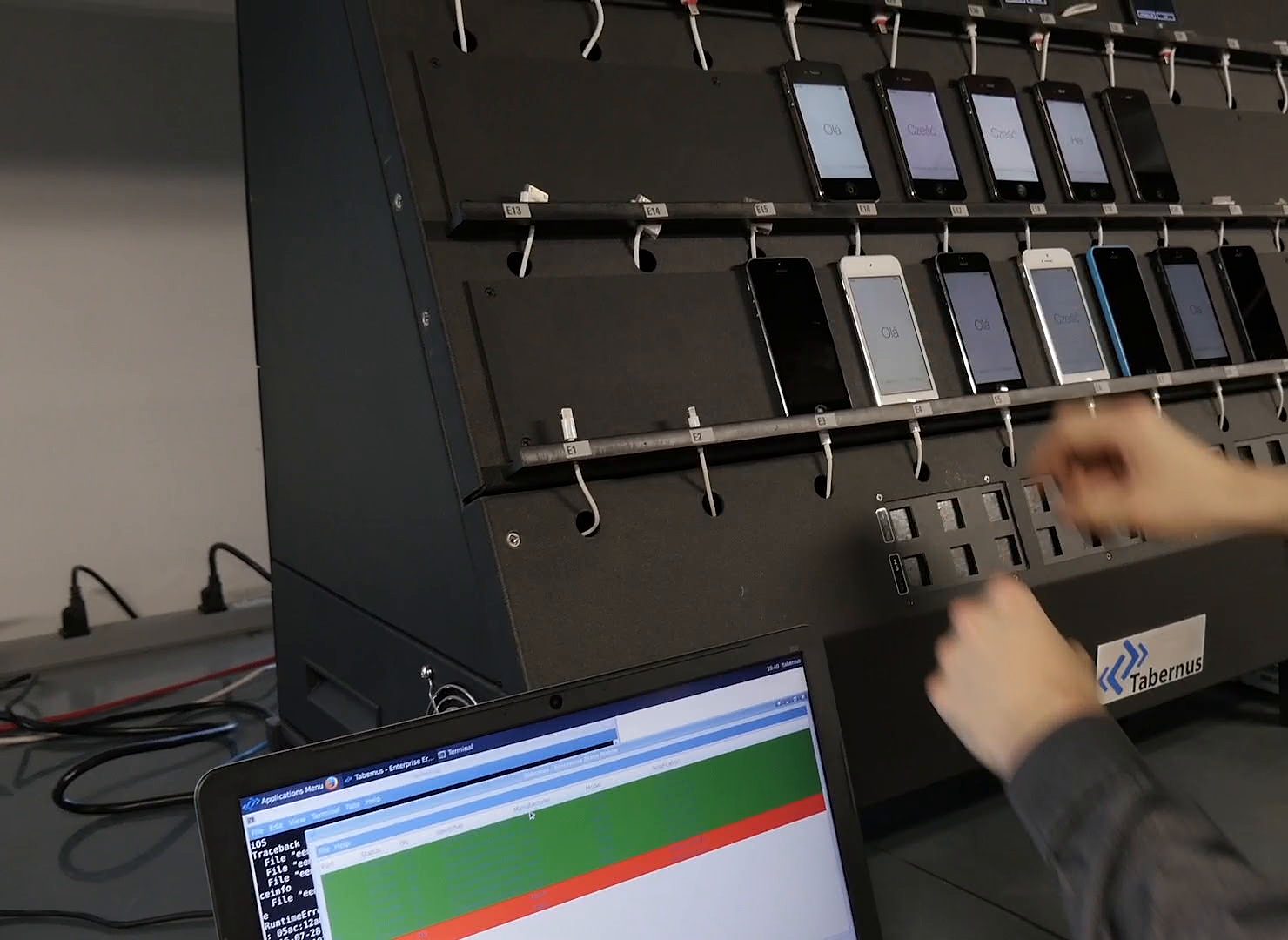 Phones plugged into a wiping rack, with the progress on a laptop screen